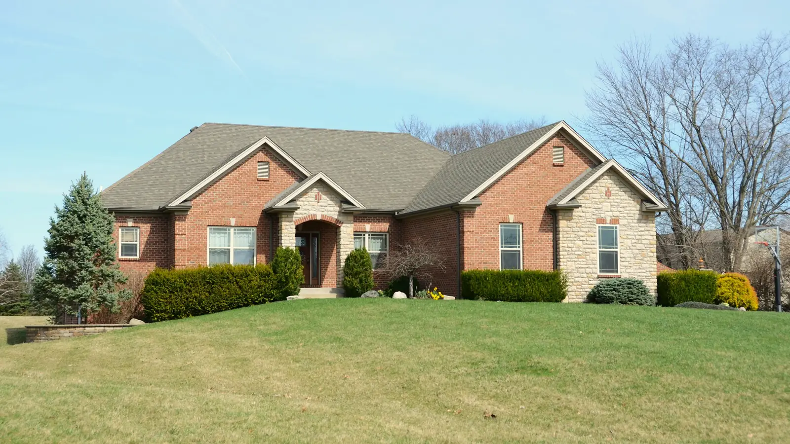 Brick home with a manicured lawn and landscaped beds